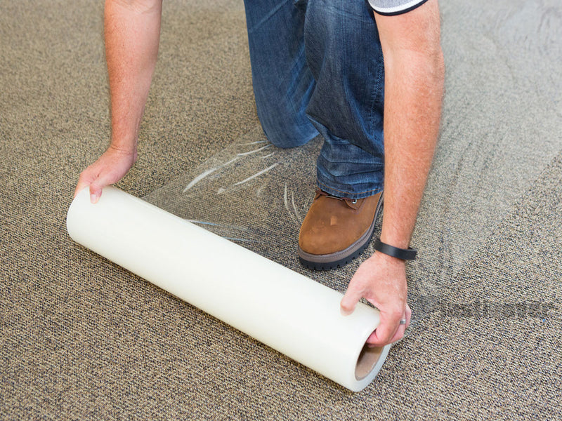 Contractor installing Plasticover carpet protection film during a remodeling project