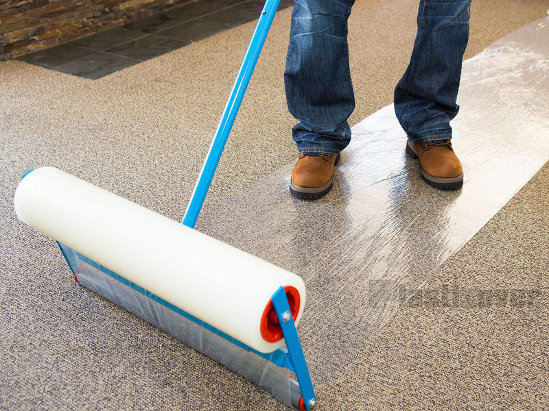 Carpet film applicator installing protective carpet film on a large carpeted area