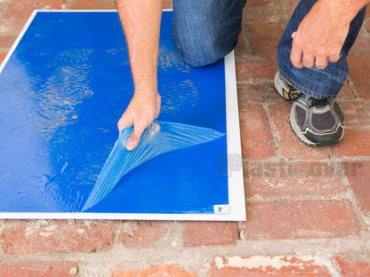 Worker removing top layer of sticky mat